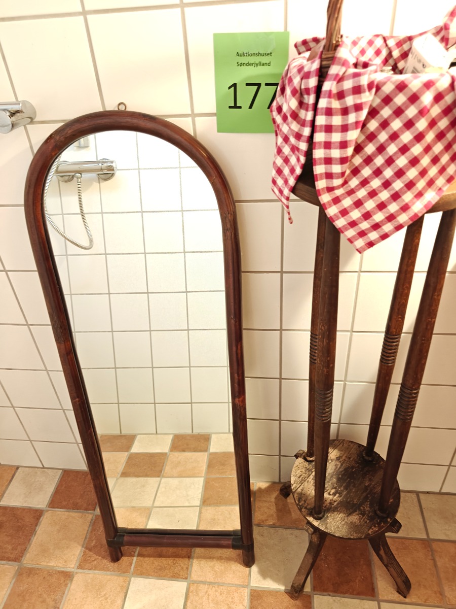 Højt spejl af rattan, blomsterstand og kurv med indhold