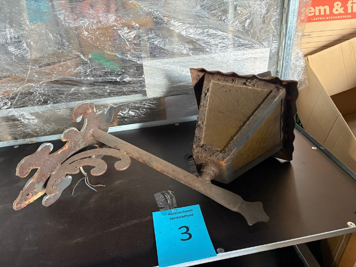 Ældre udendørs væglampe i metal med dekorativt vægbeslag – rustpatina
